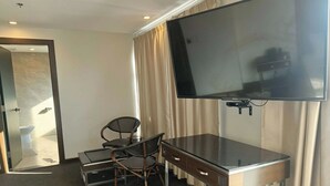A hotel room with a desk, chair, television, and curtains. - The Fields Palace Hotel Premier (Angeles City)