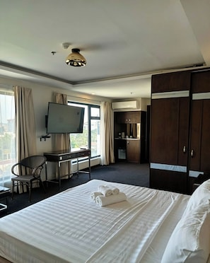 A hotel room with a bed, a desk, a chair, a TV, and a wardrobe. - The Fields Palace Hotel Premier (Angeles City)