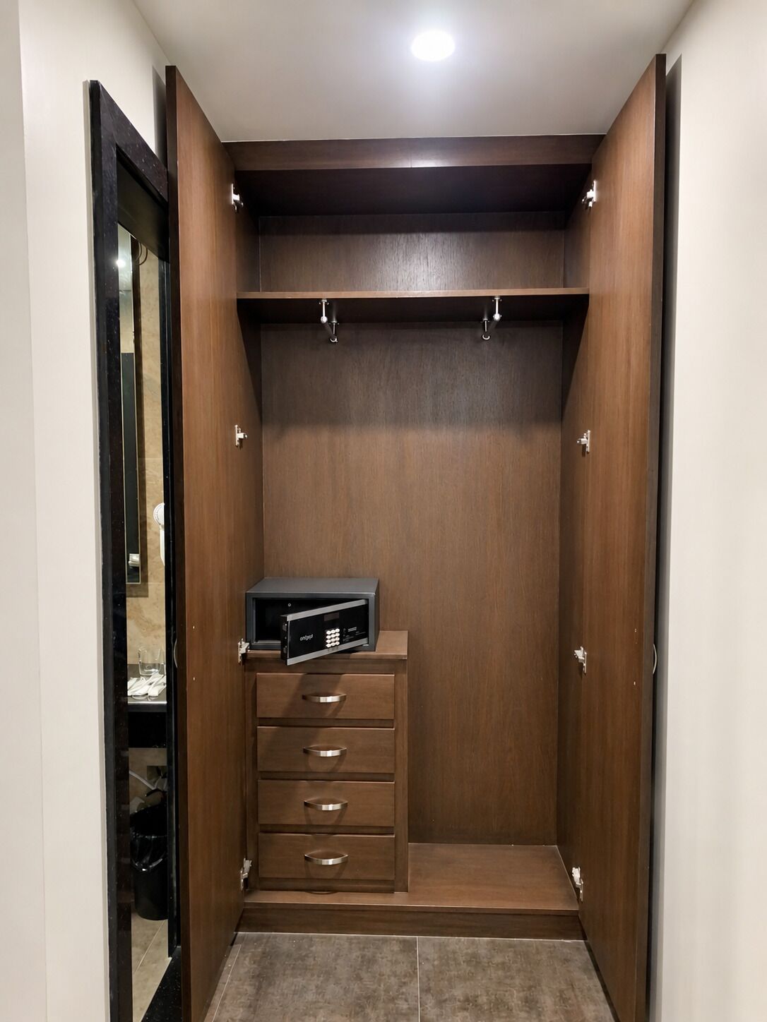 Ein begehbarer Kleiderschrank mit Holzschrank, ein kleiner Schreibtisch mit Computer und ein Spiegel.
