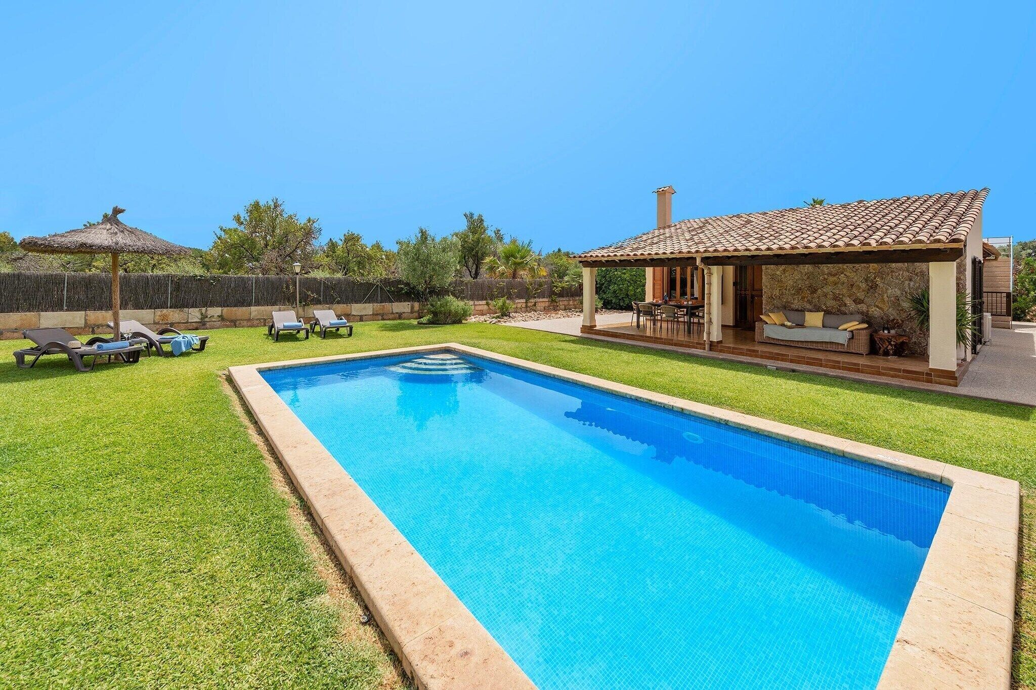 A rectangular swimming pool with a tiled edge, surrounded by a well-maintained lawn.