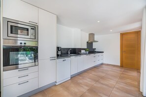 A modern kitchen with built-in appliances, a dishwasher, and a wooden door. - Central Townhouse with Pool, Pollença (Pollensa / Pollença)