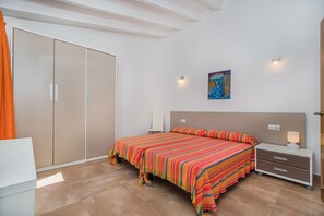 A bedroom with a bed, nightstands, a wardrobe, and a painting on the wall. - Central Townhouse with Pool, Pollença (Pollensa / Pollença)