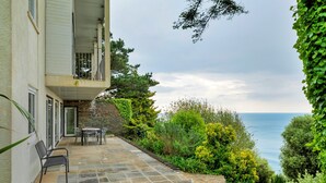 A building with a stone facade, a balcony, and a patio area with outdoor furniture. - Lavish Sea-view Holiday Home in Seaton (Torpoint)