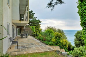 A building with a stone facade, a balcony, and a patio area with outdoor furniture. - Lavish Sea-view Holiday Home in Seaton (Torpoint)