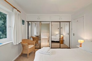 A hotel room with a bed, a chair, a bathroom, and a wardrobe with a mirror. - Lavish Sea-view Holiday Home in Seaton (Torpoint)