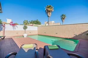 Área de piscina com espreguiçadeiras e céu azul.