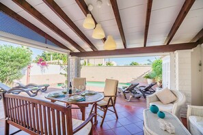 An outdoor patio with a round table, chairs, and lounge chairs. - Beach Chalet with Pool for 6 (Alcudia)
