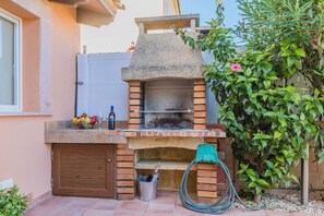 An outdoor brick oven with a hose and a bucket, a wooden door, and a window. - Beach Chalet with Pool for 6 (Alcudia)