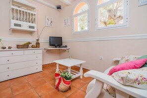 A room with a bed, a TV, a dresser, a small table, and a window. - Beach Chalet with Pool for 6 (Alcudia)