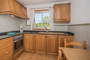 Eine kleine Küche mit Holzausstattung, einem Backofen, einer Spüle und einem Fenster mit Vorhängen.