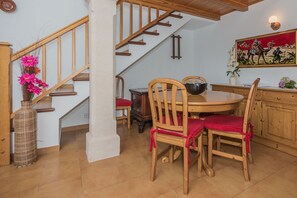 Ein Essbereich mit einem Holztisch und Stühlen, einer Vase mit Blumen und einer Treppe mit Holzgeländern.