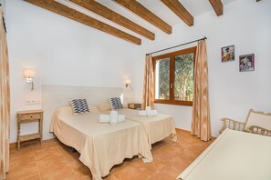A bedroom with two beds, a window with curtains, a nightstand, and a wall-mounted lamp. - Pollensa Villa with Private Pool (Pollensa / Pollença)