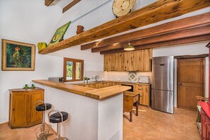 Eine Küche mit Holzschränken, einem Edelstahlkühlschrank, einer Holzeinzelküche und einem Bild an der Wand.