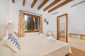 Ein Schlafzimmer mit einem Bett, einem Fenster mit Vorhängen, einem Nachttisch, einer Wandlampe und einer Tür mit Leiter.