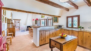 A spacious kitchen with wooden cabinets, a central island, and a dining area with chairs. - Pollensa Villa with Private Pool (Pollensa / Pollença)
