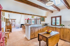 Eine geräumige Küche mit Holzausstattung, einer zentralen Kochinsel und einem Essbereich mit Stühlen.