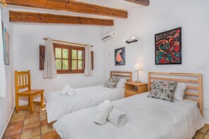 A room with two beds, a window, a chair, a lamp, and artwork on the walls. - Villa near Pollensa Old Town (Pollensa / Pollença)