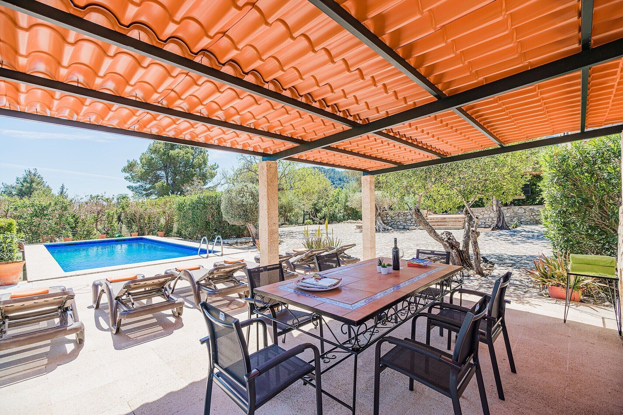 Une terrasse extérieure avec une piscine, une table à manger, des chaises et une pergola.