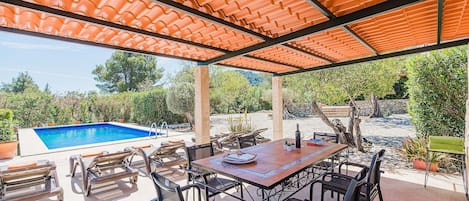 Une terrasse extérieure avec une piscine, une table à manger, des chaises et une pergola.