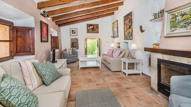 A cozy living room with a fireplace, wooden beams, and various artworks. - Villa near Pollensa Old Town (Pollensa / Pollença)