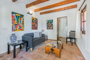 Ein Wohnzimmer mit einer Couch, einem Couchtisch, einem Beistelltisch mit einer Vase und drei abstrakten Bildern an der Wand.