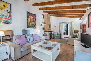 Una sala de estar con un sofá, una mesa de centro con adornos, una chimenea y un televisor.