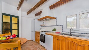 A kitchen with wooden cabinets, a stove, a sink, and a window. - Villa near Pollensa Old Town (Pollensa / Pollença)