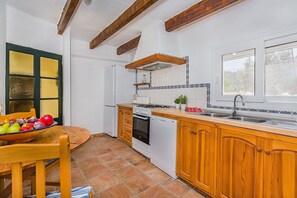 A kitchen with wooden cabinets, a stove, a sink, and a window. - Villa near Pollensa Old Town (Pollensa / Pollença)