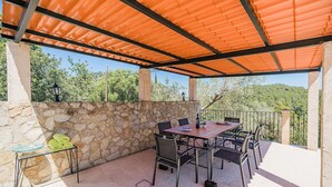 An outdoor patio with a stone wall, a table with chairs, and a tiled roof. - Villa near Pollensa Old Town (Pollensa / Pollença)