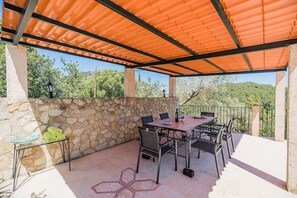 An outdoor patio with a stone wall, a table with chairs, and a tiled roof. - Villa near Pollensa Old Town (Pollensa / Pollença)