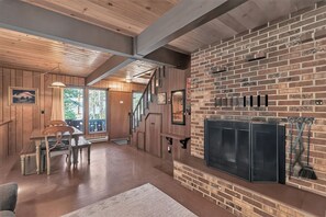 Un vaste espace de vie doté d’une cheminée, d’un plancher en bois et d’un coin repas avec une table et des chaises.