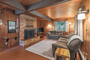 A cozy living room with a brick fireplace, a flat-screen TV, a comfortable sofa, and a wooden coffee table.