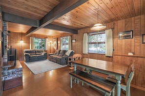 A cozy cabin interior with a wooden ceiling, a sofa, a dining table, and a bench. - Government Camp Cabin | Fireplace & Balcony (Government Camp)