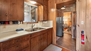 Una cucina con mobili in legno, un lavello in acciaio inossidabile e un frigorifero.