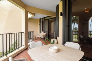 A balcony with a table and chairs, a view of the outdoors, and a door leading to another room. - Boho 2BR Retreat - Ocean View Terrace & Pool (Palmas del Mar)