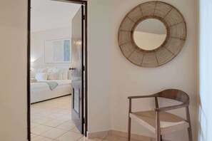 Ein Zimmer mit einem Bett, einem Sessel und einem wandmontierten Spiegel.