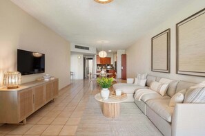 Ein modernes Wohnzimmer mit einer Couch, einem Fernseher und einem Essbereich mit Tisch und Stühlen.