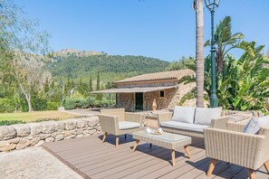 Eine Terrasse mit Korbmöbeln, einer Steinmauer und Blick auf einen Berg.