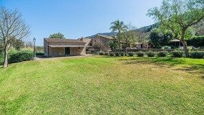 A stone building with a flat roof, surrounded by a grassy area and trees. - Historic Villa with Mountain Views, Mallorca (Pollensa)
