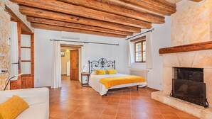 A bedroom with a bed, a fireplace, a wooden ceiling, and a tiled floor. - Historic Villa with Mountain Views, Mallorca (Pollensa)