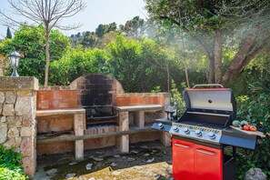Un espace barbecue extérieur équipé d’un four en briques et d’un gril à gaz.
