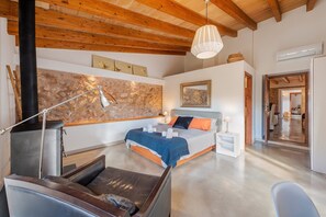 Ein modernes Schlafzimmer mit einem Bett, Nachttischen, einer Lampe, einem Kamin und einem großen Spiegel.