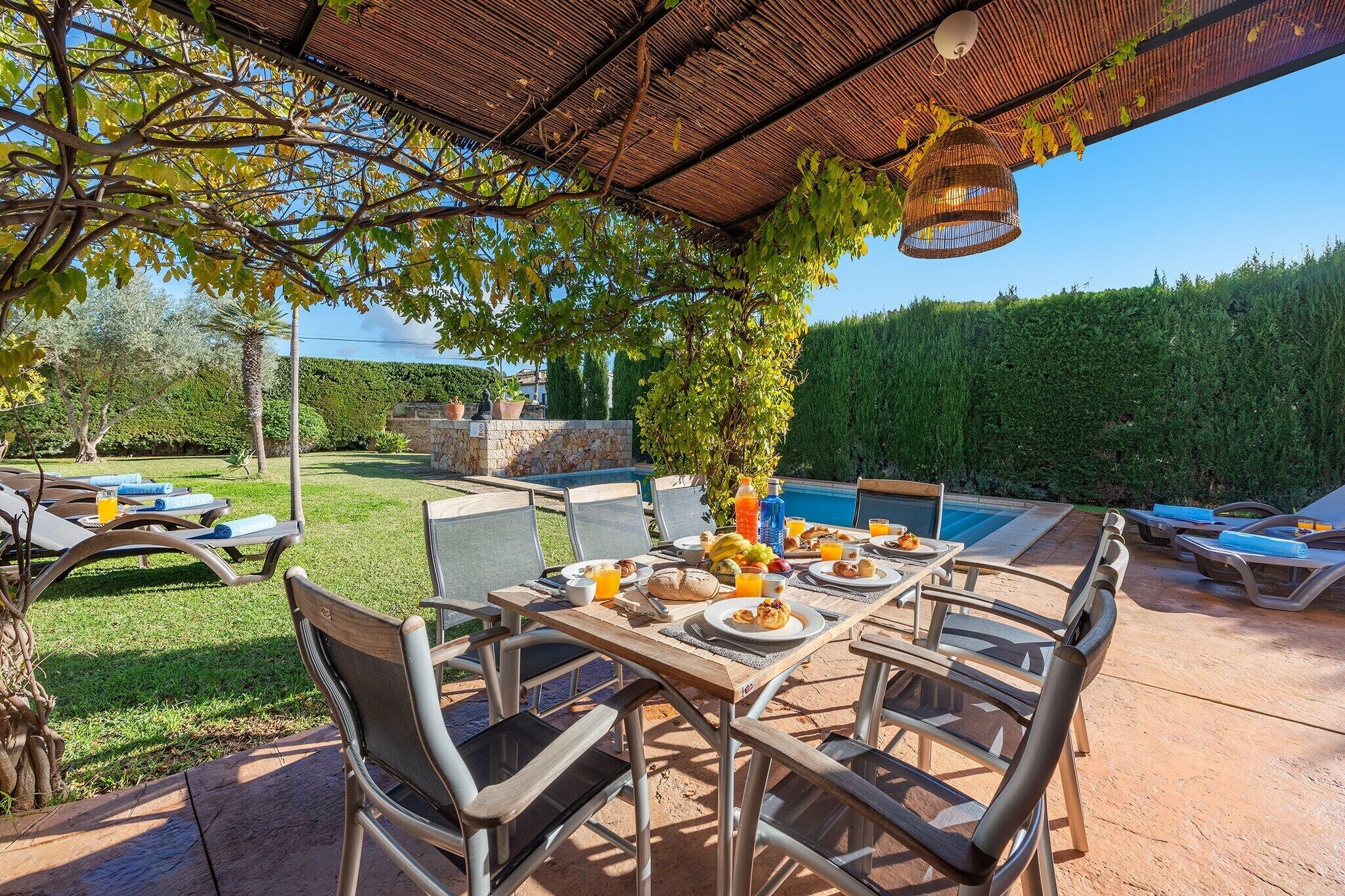 An outdoor dining area with a pool, chairs, and a table set for breakfast.