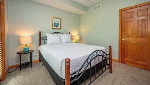 Ein Schlafzimmer mit einem Bett, zwei Nachttischlampen, einem Deckenventilator, einer Tür und einem gerahmten Bild an der Wand.