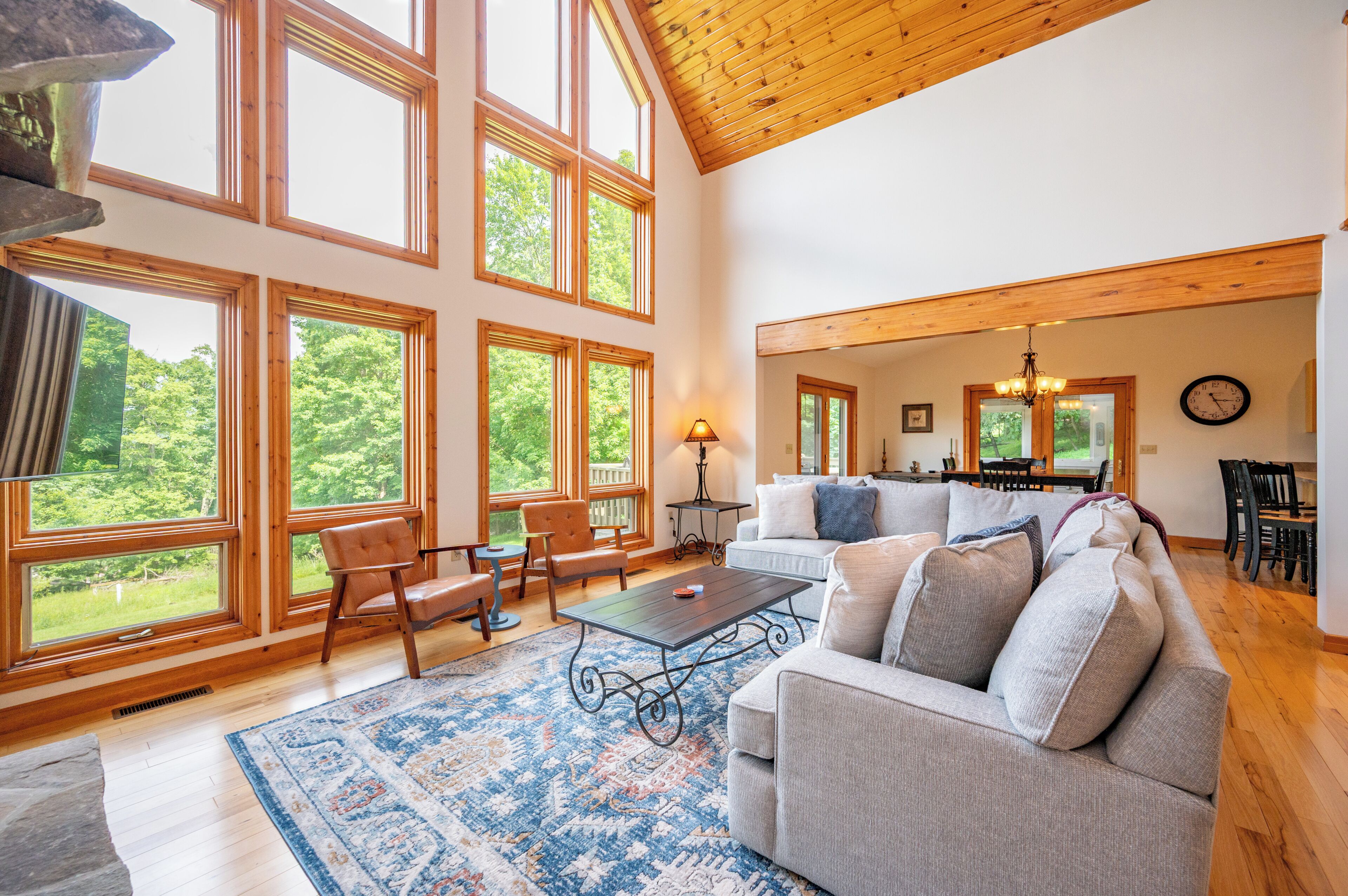 A spacious living room with large windows, a sofa set, a coffee table, and a dining area.