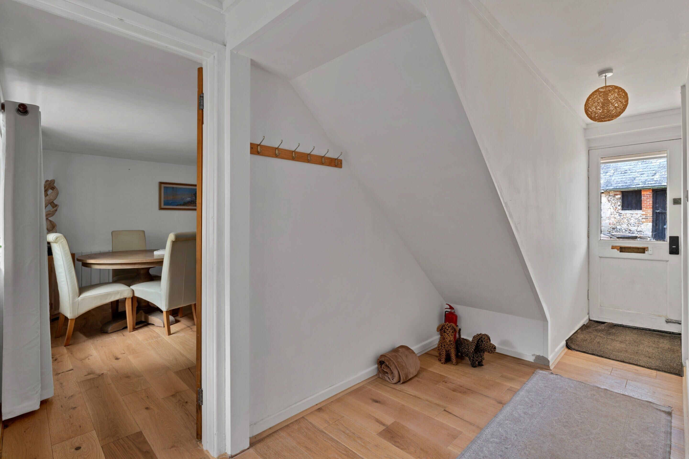A room with a dining area, a coat rack, a fire extinguisher, and a dog.