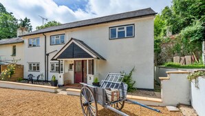 A two-story house with a front porch, a driveway, and a wheelbarrow. - Romantic North Wales Meadow Cottage (Andover)