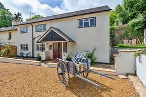 A two-story house with a front porch, a driveway, and a wheelbarrow. - Romantic North Wales Meadow Cottage (Andover)