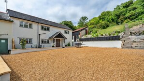 A two-story house with a gravel driveway and a stone wall. - Romantic North Wales Meadow Cottage (Andover)