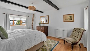 A bedroom with a bed, dresser, chair, and a radiator. - Romantic North Wales Meadow Cottage (Andover)